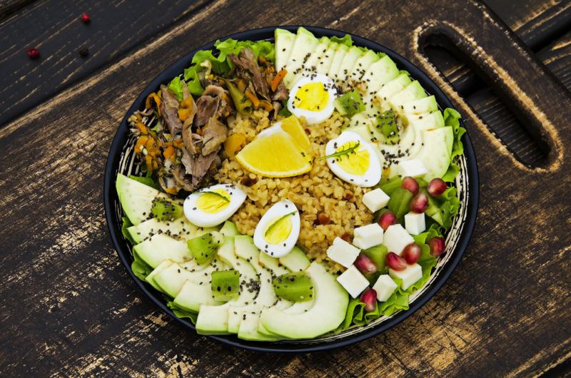 A large black bowl with healthy ingredients like bulgar porridge and beef