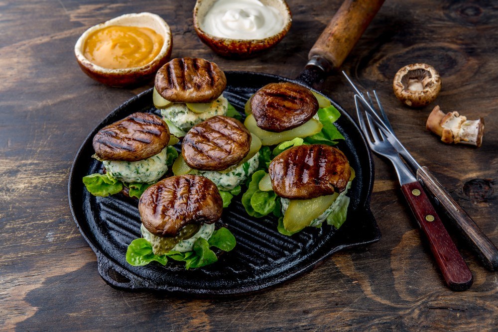 A black dish with six burgers made with grilled mushrooms