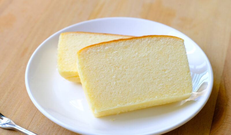 on a wooden surface is a white ceramic plate with a couple of Butter cake