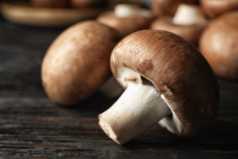 A close up shot of button mushrooms on a wooden table