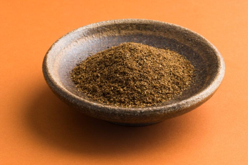 on an orange surface is a brown clay bowl with Cajun seasoning