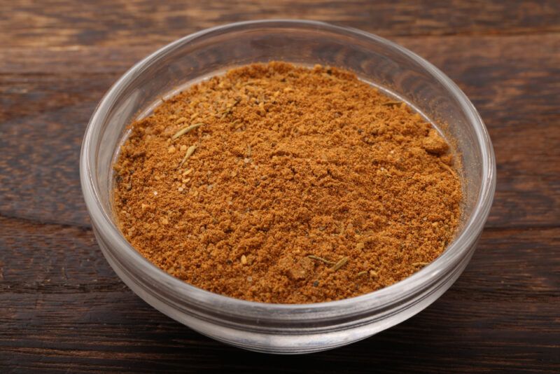 on a brown wooden surface is a clear glass bowl full of Cajun spice