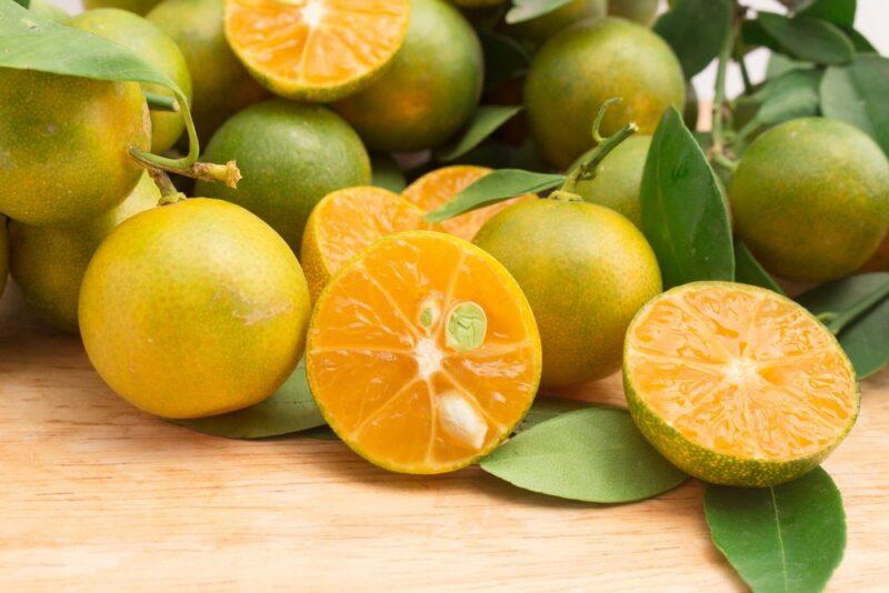 Green calamansi limes. A few have been cut in half to reveal their bright orange flesh