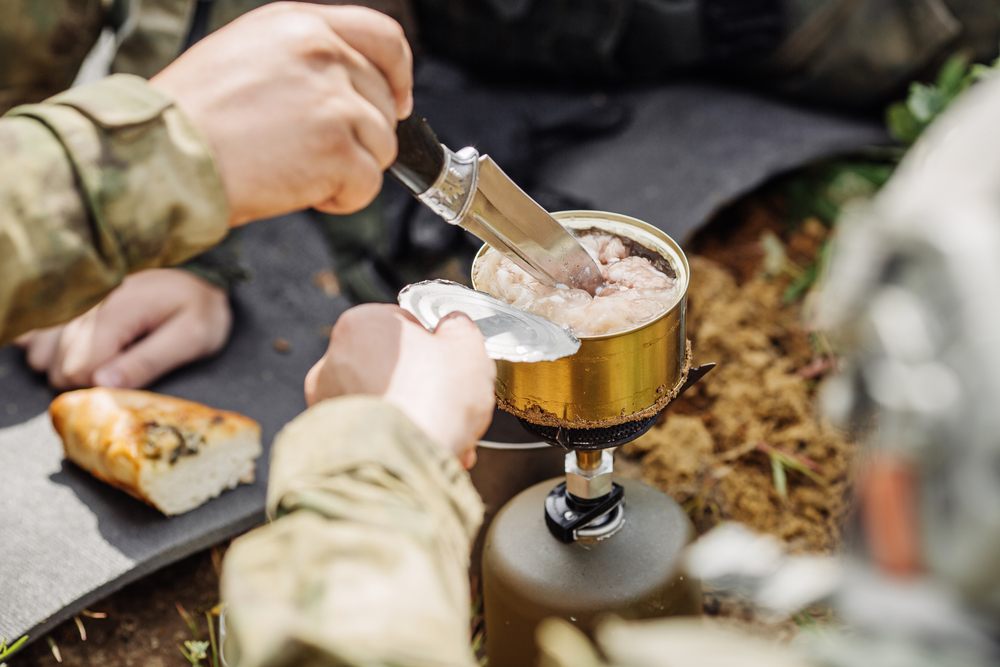 A camper or hiker digging into a can of meat