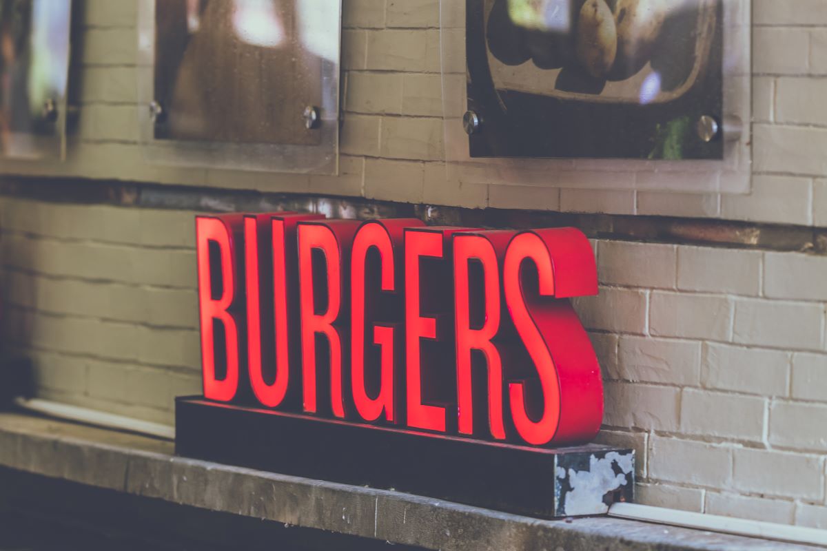 Burger of the Month Clubs - Red sign that says burgers in capital letters against a white brick wall