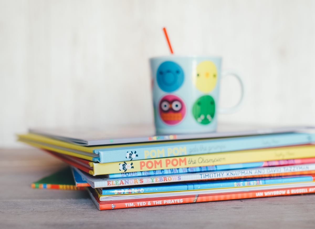  Children's Book of the Month Clubs - stack of kids books and colorful cup in the background with a straw