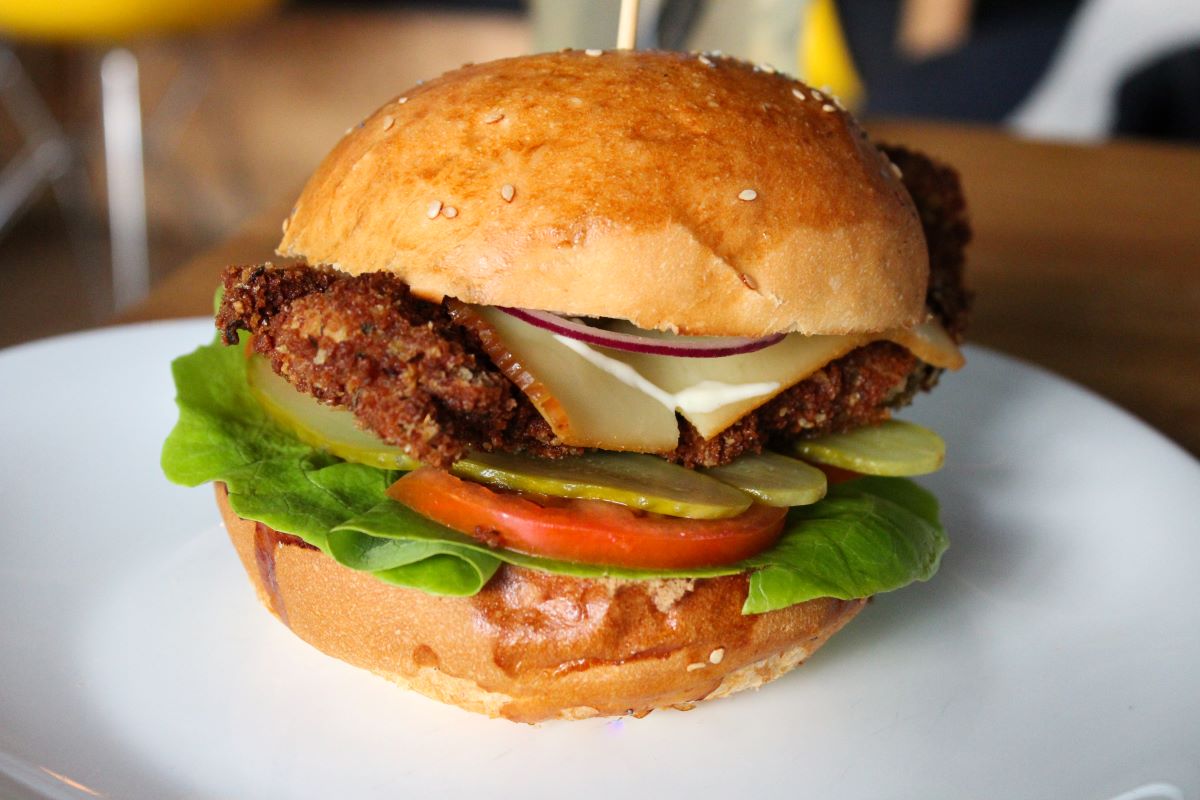 Burger with sesame bun with pickles, cheese red onion, lettuce and tomato