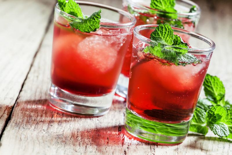 Three short glasses containing a Cape Codder cocktail with ice and peppermint leaves