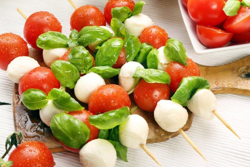 Caprese salad kebabs on a plate, made using cherry tomatoes, basil, and mozzarella