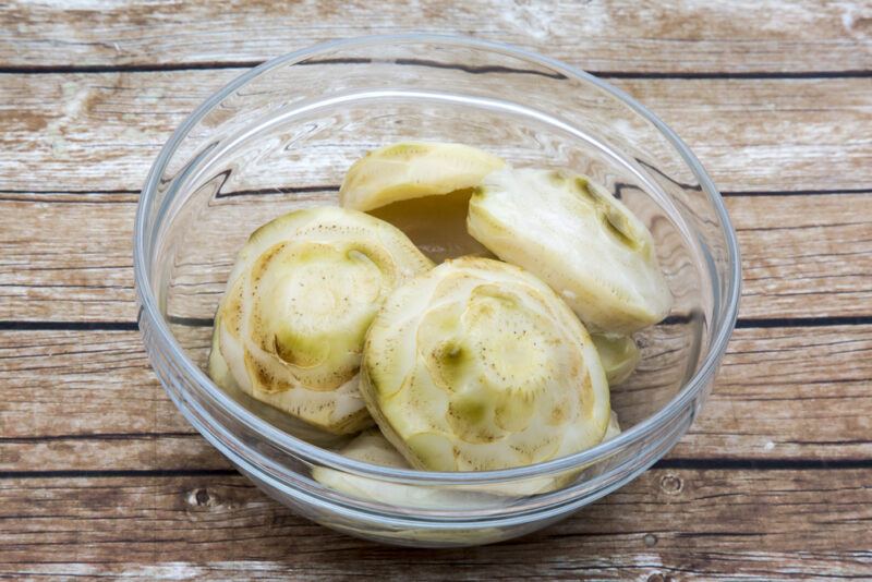 on a wooden surface is a clear glass bowl of cardoon hearts