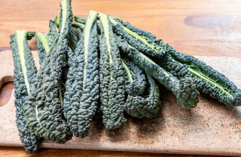 on a wooden surface is a wooden chopping board with Cavolo Nero on it