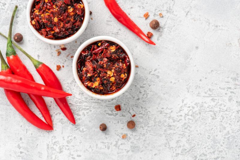 Hot,Sauce,Of,Red,Dry,Chili,Peppers,With,Soy,Oil | Food For Net Five cayenne peppers and two white bowls of cayenne pepper paste rest on a white surface.