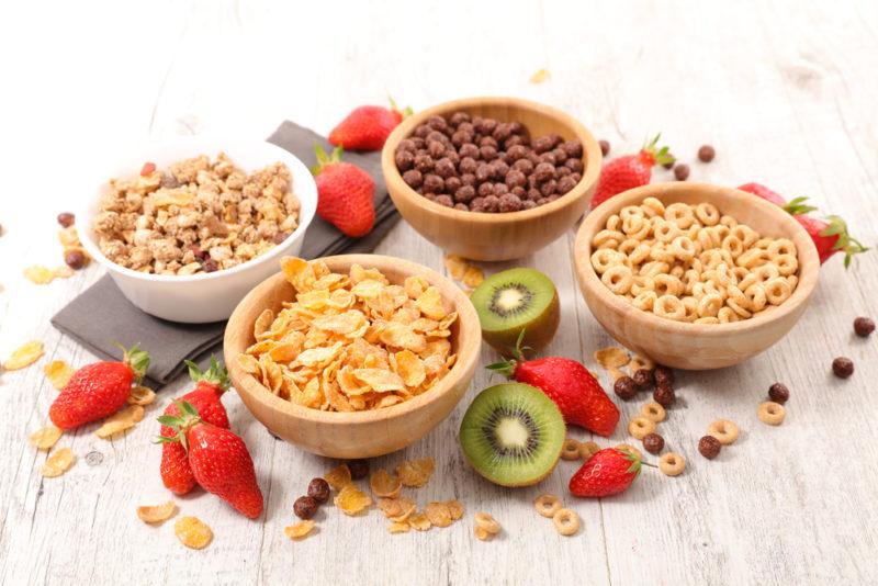 Four bowls of breakfast cereal with various fresh fruit on the table