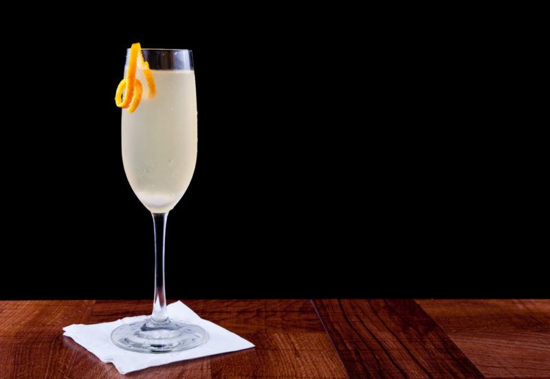 A champagne cocktail on a wooden table against a black background