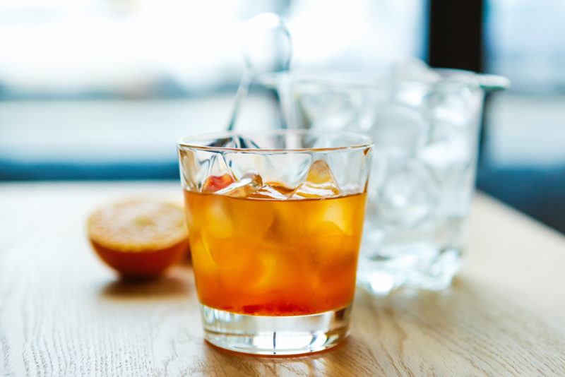 A glass of Chatham artillery punch on a table with a bucket of ice in the background