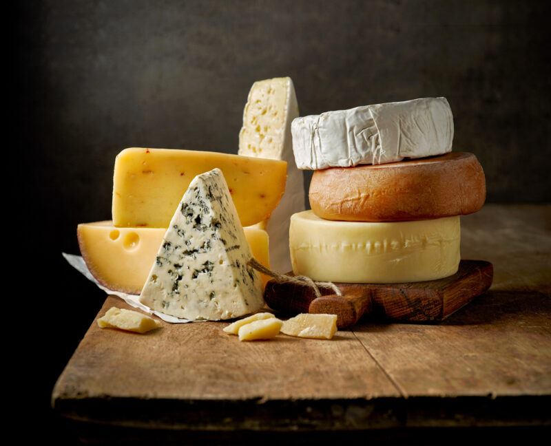 Several types of cheeses rest on a wooden tabletop.