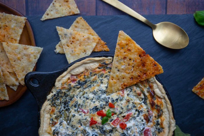 A dish with spinach dip and various taco chips