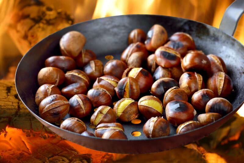 A fry pan over a fire being used to roast chestnuts