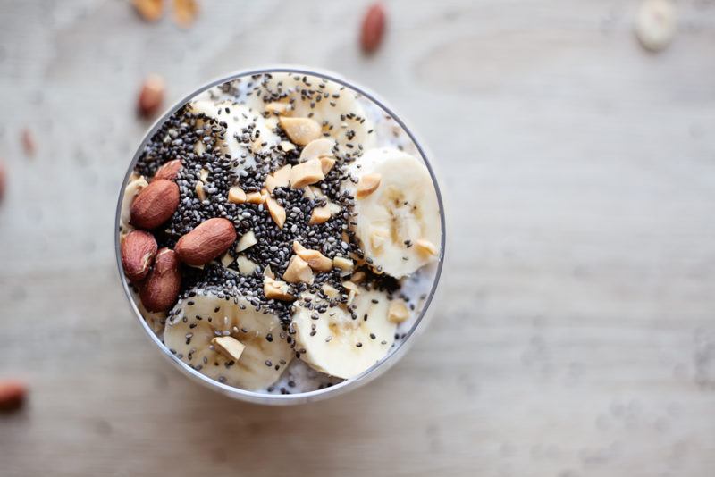 A smoothie bowl with various toppings, including bananas, nuts and chia seeds