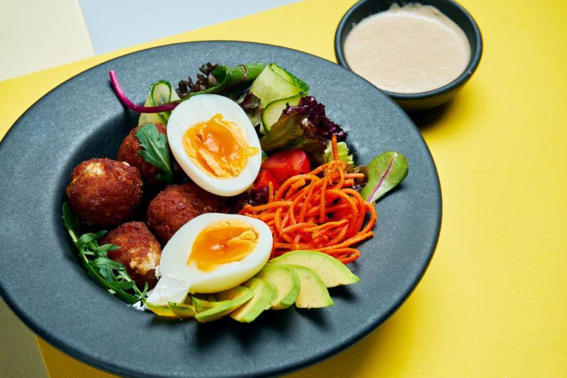 A blue plate with chicken croquettes, eggs and veggies