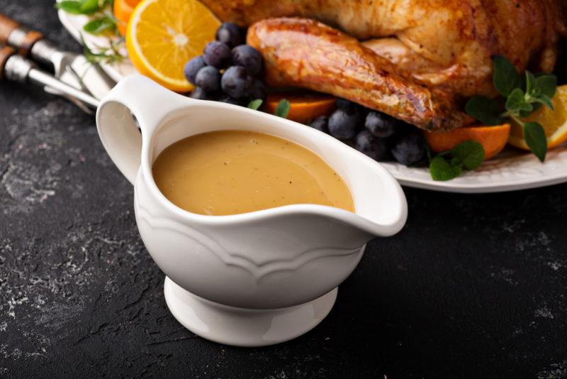 A gravy boat with chicken gravy next to a roast chicken