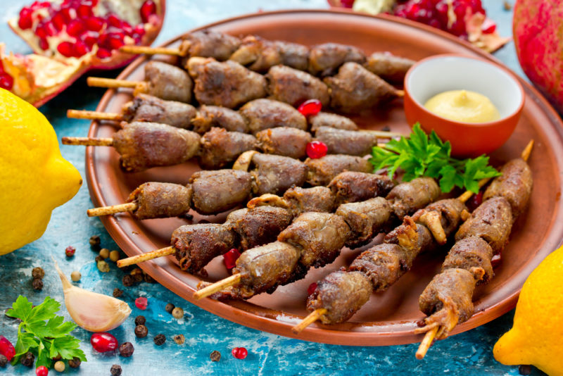 A brown plate or dish with a selection of chicken hearts on skewers