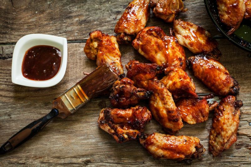 Cooked chicken wings next to a pastry brush with some glaze