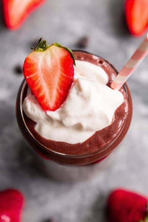 A glass containing a chocolate strawberry paleo and keto smoothie, with cream and a strawberry on top