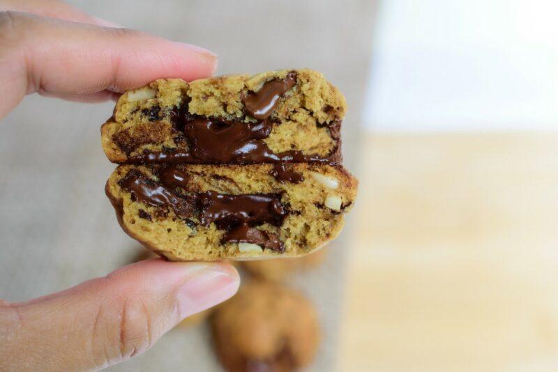 Someone holding a chocolate chip cookie that's been cut in two and stuffed with a truffle