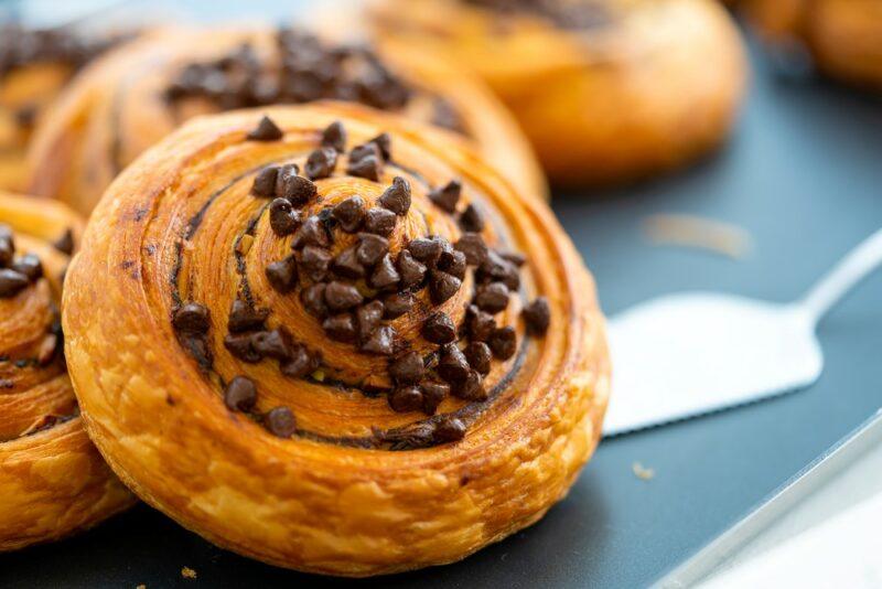 A blue surface with a cake knife and a selection of chocolate chip danishes