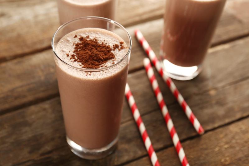 Three glasses of chocolate shake on a table with straws