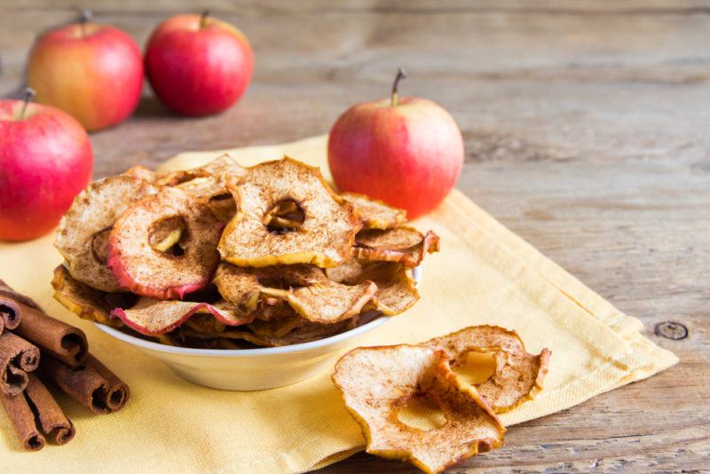 Cinnamon apple crisps on a placemat with cinnamon and apples