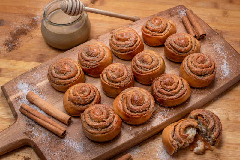 12 cinnamon scrolls on a wooden board