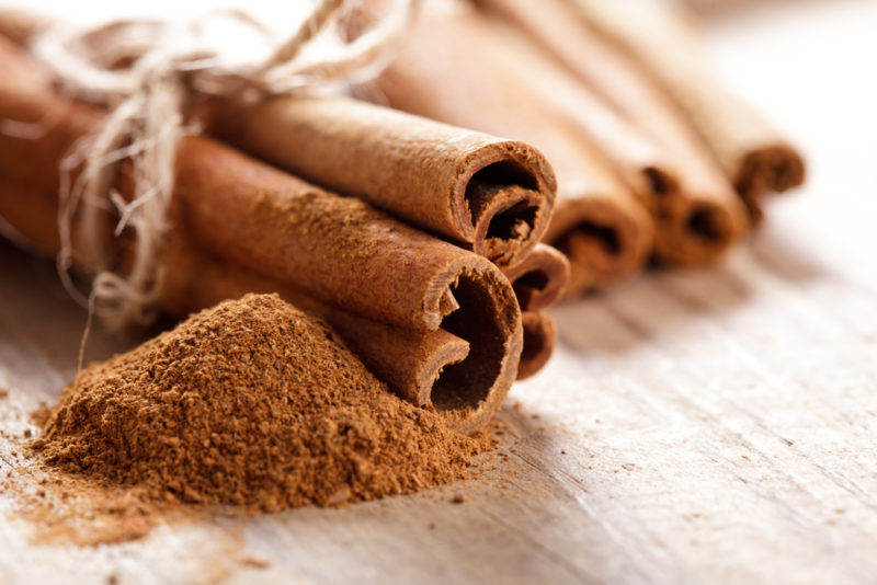 Cassia cinnamon sticks on a table with powdered cinnamon as well