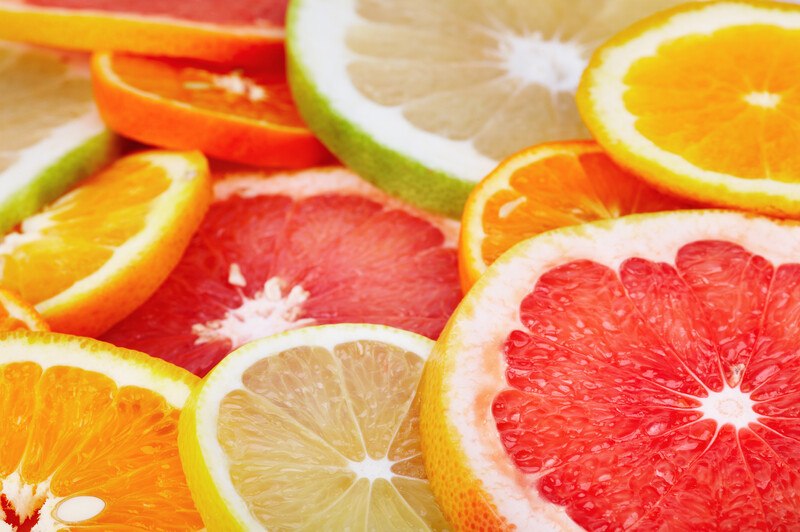 This photo is a closeup of slices of several types of citrus fruits in yellow, orange, pink, and green.