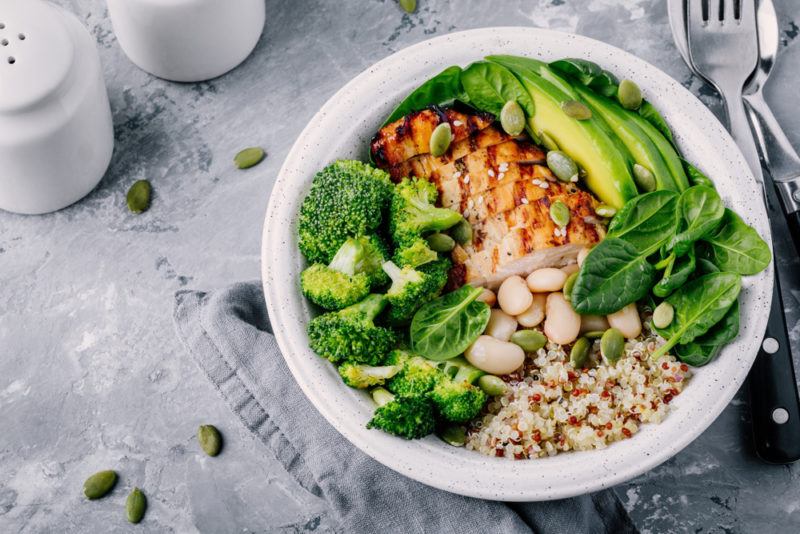 A white bowl with sliced chicken and avocado