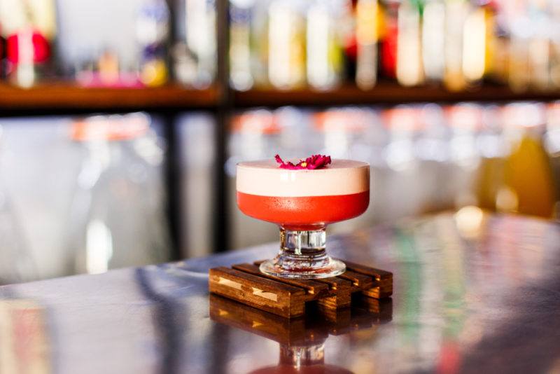 A Clover Club coktail in front of a bar