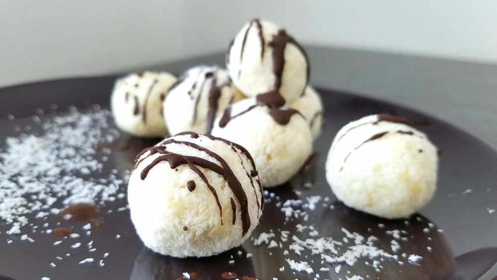 A selection of chocolate and coconut fat bombs on a black plate