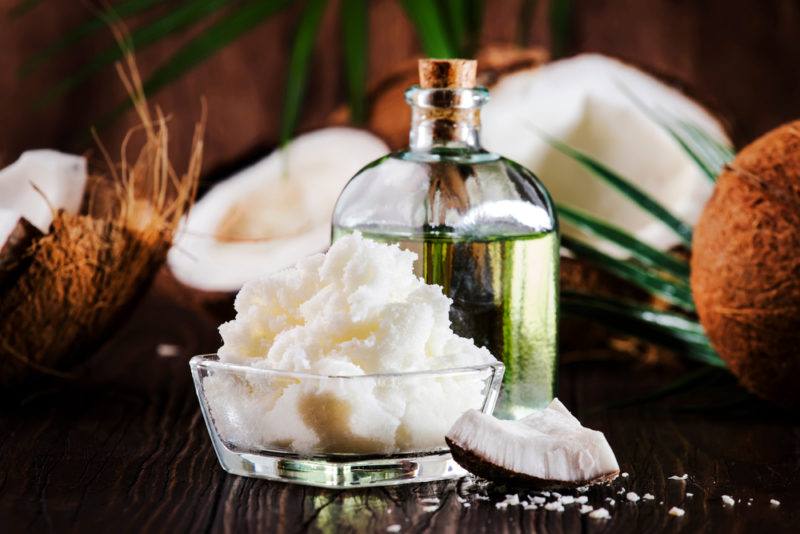 Coconut oil and MCT oil on a table with coconuts and leaves in the background