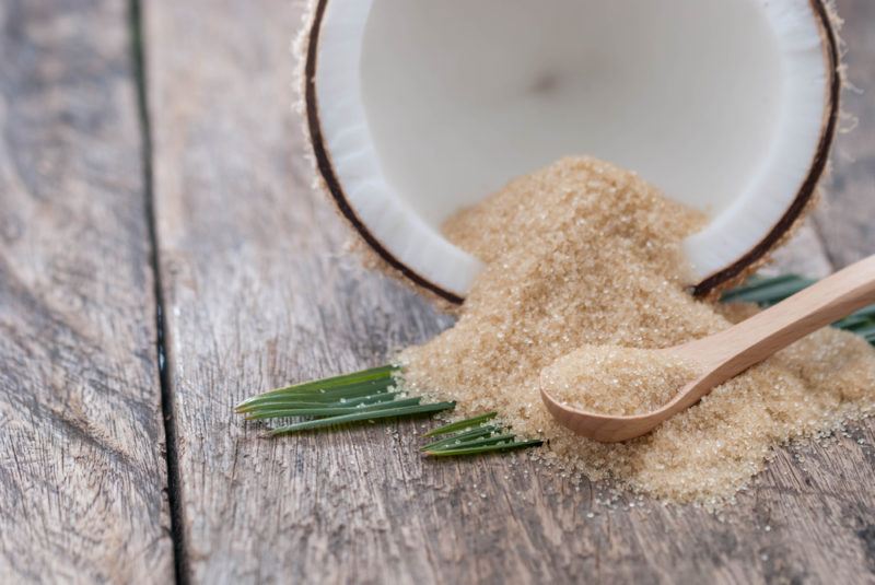 Half of a coconut with coconut sugar pouring out of it