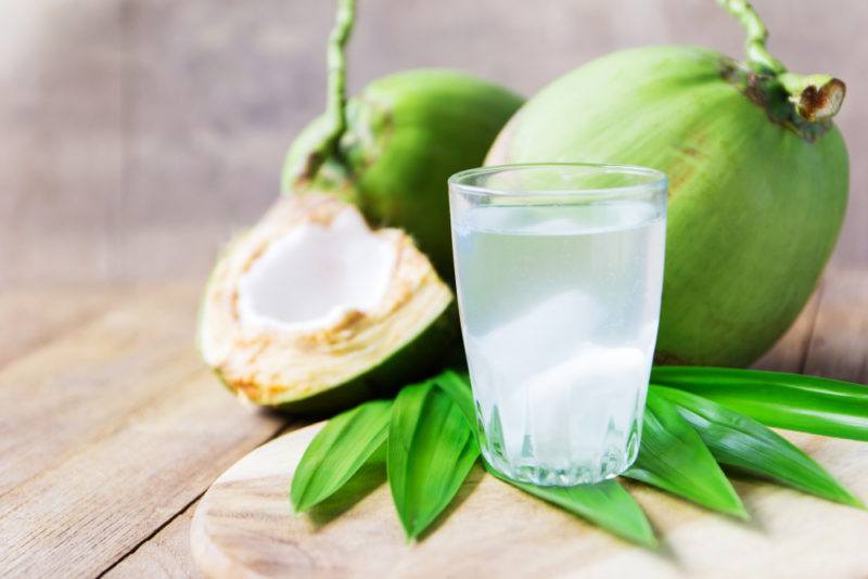 Two green coconuts with a glass of coconut water