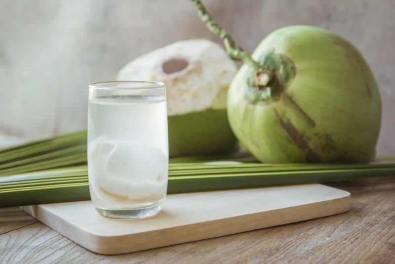 A glass of coconut milk and green coconuts