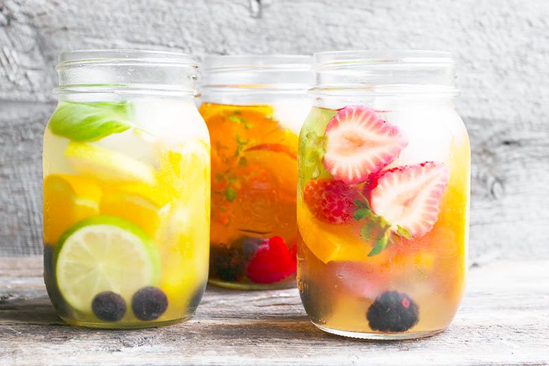 Three mason jars containing cold brewed tea, plus fresh fruit, each with a different flavor profile.