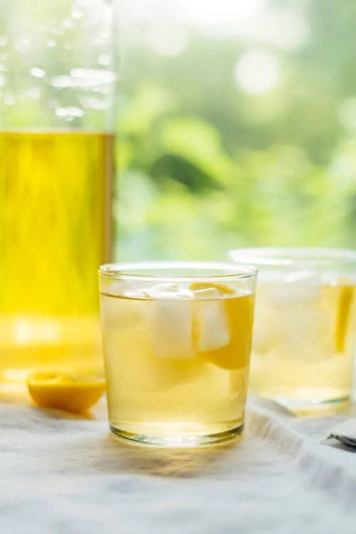 Two glasses of cold brew iced tea from Cookie and Kate, next to half a lemon and a pitcher of the tea