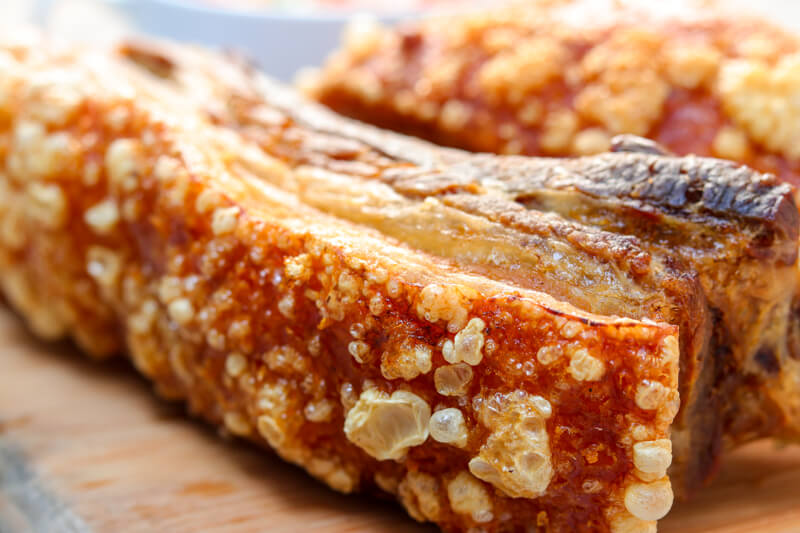 A wooden board with two cooked pieces of pork belly