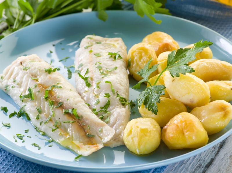 A light blue plate with cooked potatoes and cooked cod