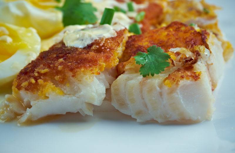 Cooked haddock for breakfast on a white plate with eggs