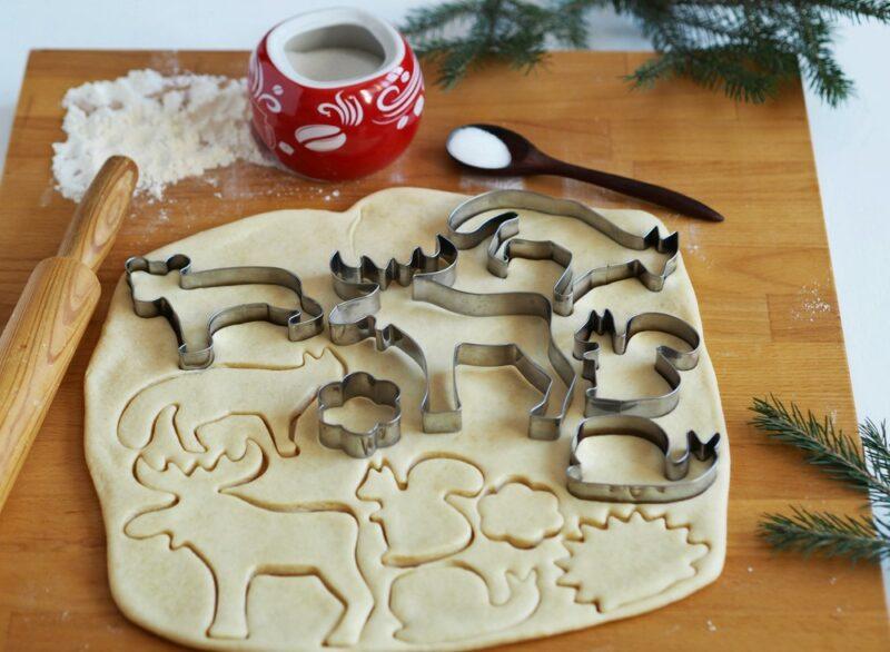 A light colored piece of cookie dough that's being cut with animal-shaped cookie cutters