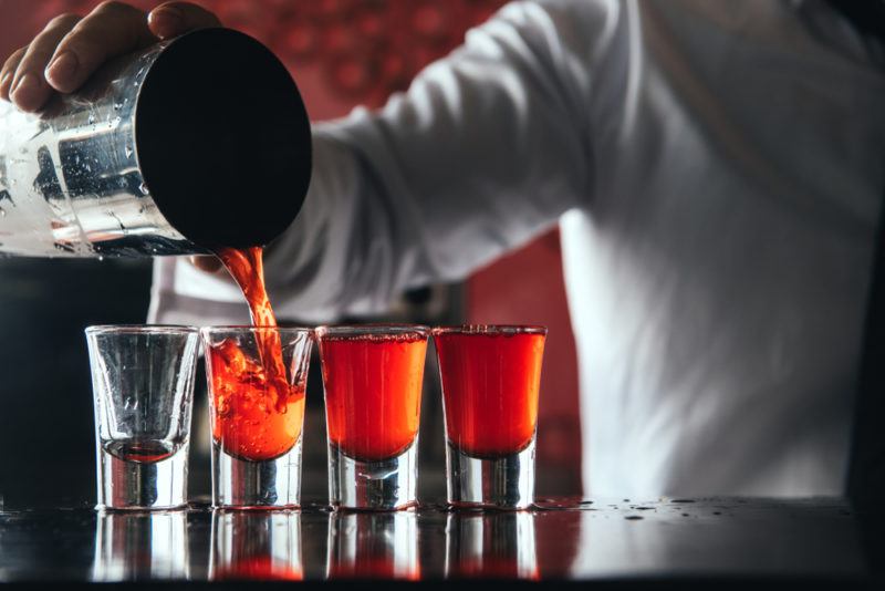 A bartender pouring Cosmopolitan shots