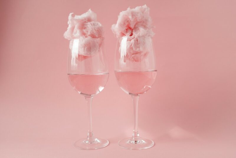 Two wine glasses with pink cotton candy vodka and cotton candy in the top